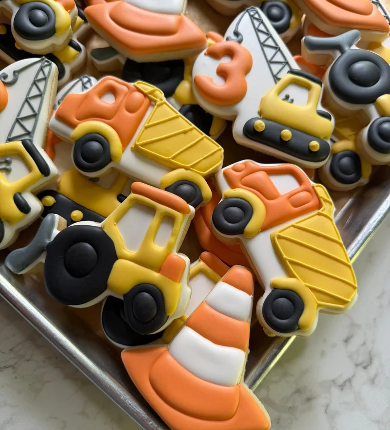 Dump truck and crane cookies in orange and yellow for a construction party.