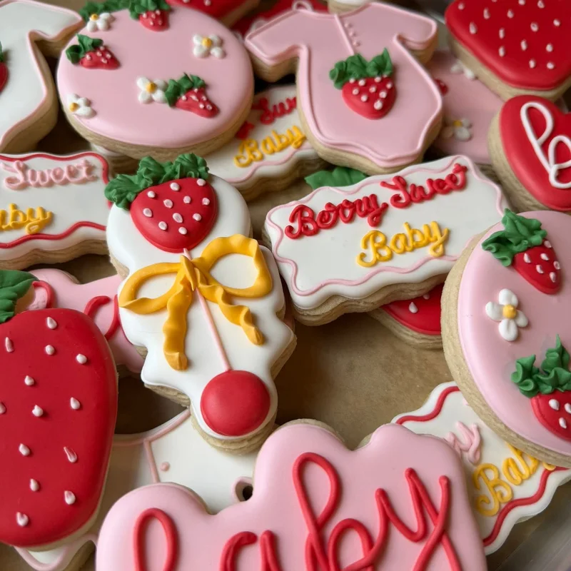 Strawberry-themed baby shower cookies reading berry sweet.