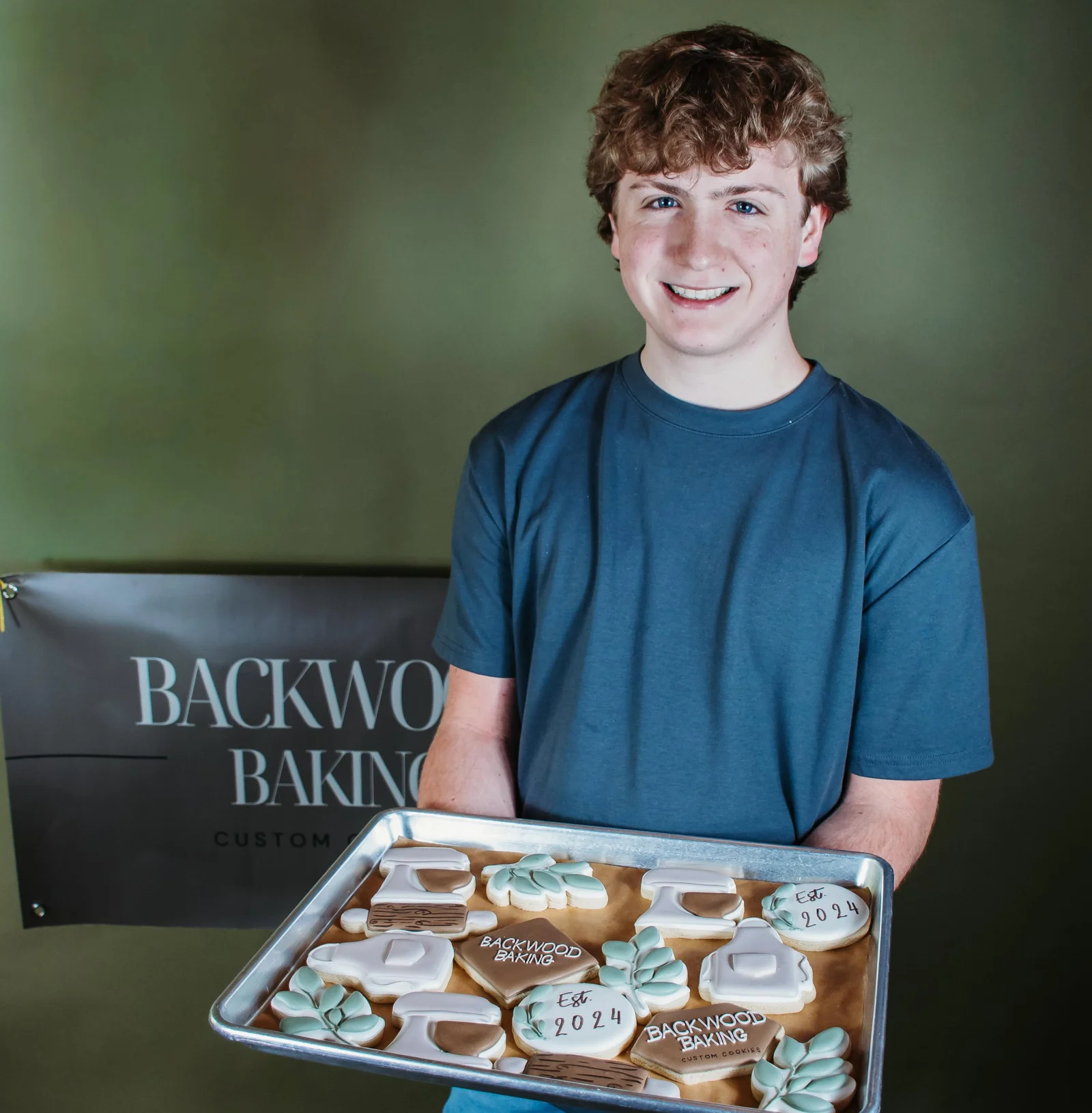 Luke Fox holding a sheet tray of Backwood Baking custom cookies.