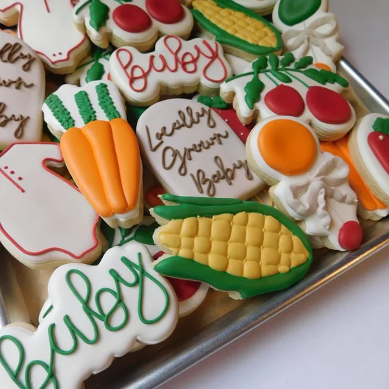 Baby shower cookies reading 'locally grown baby' with carrots and corn.